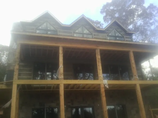 Dormers and porch framing on a large log home under construction — Roof Coating work by our crew in Rocky Mount