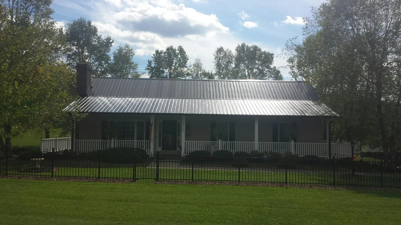 Gray metal roof on a brick ranch with a full width front porch — Gutter Guard Installation work by our crew in Rocky Mount