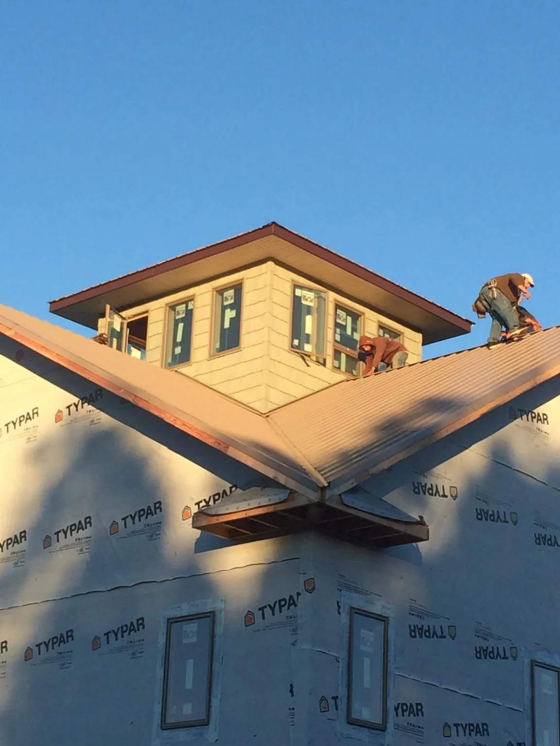 Roofers working around a rooftop cupola on a new metal roof at sunset — Roof Waterproofing in Rocky Mount by Roofing Brothers